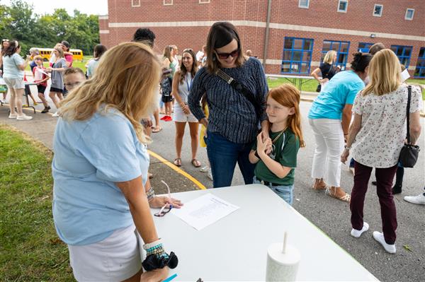 teacher waving at student and parents